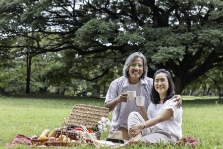 Asian senior couple drinking coffee and picnic at park.