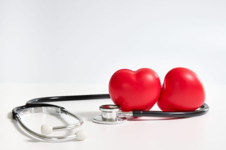 two red hearts surrounded by a stethoscope on white background