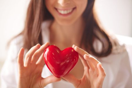 Close-up of smiling female holding red heart