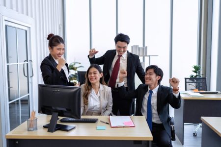 Employee on line reading good news mail from PC screen excited and happy together from their winning