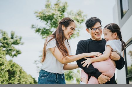 Happy Asian family mother, father and daughter having fun time outside their home